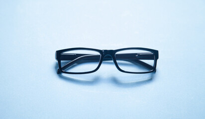 Fototapeta na wymiar Black eyeglasses on the blue background.