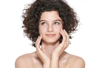 Teenager skincare. Beautiful teenage girl with gorgeous curly hair and perfect skin touching her...