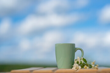 Blue cup on a wooden table and cloudy blue sky background