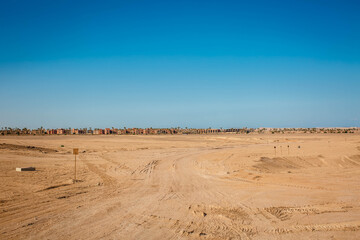 Fototapeta na wymiar Dry desert landscape. Hot lifeless sand of desert and blue sky in summer sunny day. Flat desert of Egypt. Travel and tourism concept.