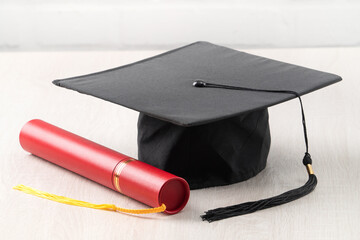 Graduation academic cap with diploma on wooden table background.