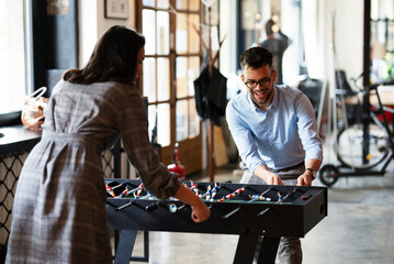 Colleagues having fun at work. Businessman and businesswoman playing table soccer.