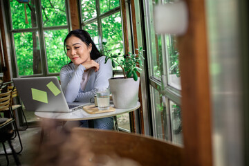Young Asian woman working using laptop in coffee shop.