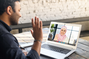 Back view multiracial middle-eastern man using mobile computer app for video meeting with female...