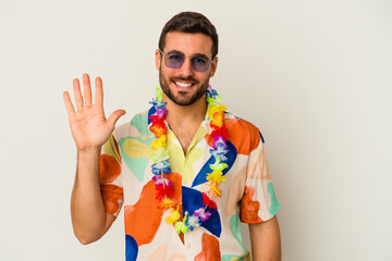Young caucasian man dancing on a hawaiian party isolated on white background smiling cheerful...