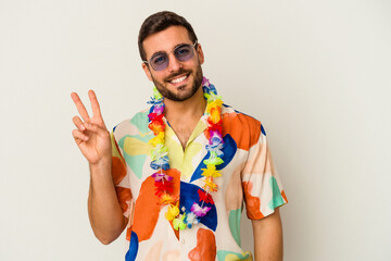 Young caucasian man dancing on a hawaiian party isolated on white background joyful and carefree...