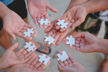 Hand of diverse people connecting jigsaw puzzle. Concept of partnership and teamwork in business