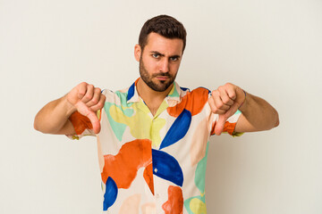 Young caucasian man isolated on white background showing a dislike gesture, thumbs down....