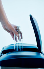 man throws a glass bottle in a home recycling bin