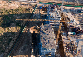 Tower cranes in action at construction site. Crane during formworks. Soil Compactor leveling ground for construct of foundation for residential building. Construction Foundation in pit. Out of focus