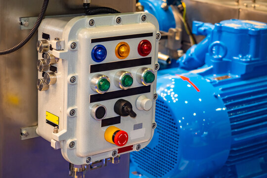 Production equipment launch panel. Stationary control panel for starting and controlling equipment. Production panel with multi-colored buttons. Electric motor behind controller manufactory.