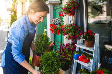 Young adult woman working in city street flower shop.Small business concept.