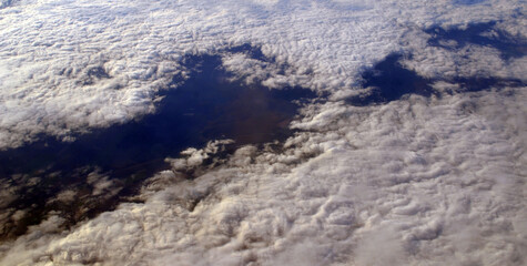 Aerial view of clouds and sky. Bird eye view from airplane window. Clouds panorama from airplane. 