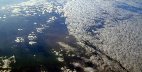 Aerial view of clouds and sky. Bird eye view from airplane window. Clouds panorama from airplane. 