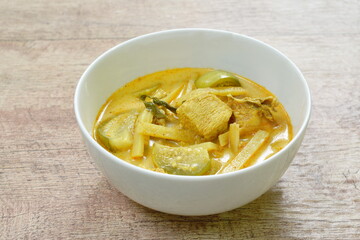 spicy boiled slice fresh bamboo shoot and eggplant with chicken in coconut milk curry soup on white bowl