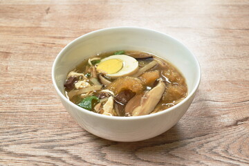 braised fish maw with bamboo shoot topping slice chicken and boiled egg in red gravy soup on bowl