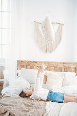 cute teenage girl lies on the bed with pillows in a bright room