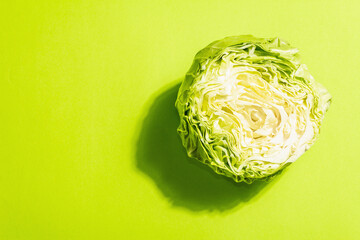 Fresh young cabbage, half a head in bright green background