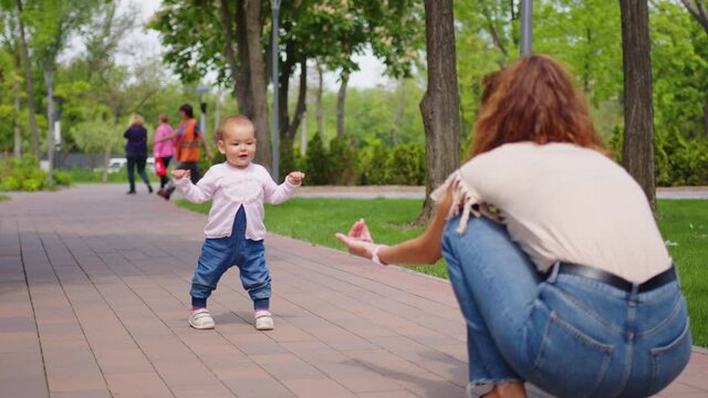 Baby girl takes first steps. Concept of family summer vacation, outdoor games, first steps, child development.