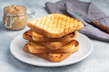 Bread toast crispy for sandwiches on a plate on a gray concrete table. A jar of chicken pate.