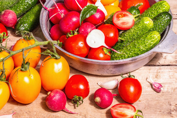 Assortment of ripe organic farmer red and yellow tomatoes, cucumbers, radish, garlic, and fresh basil leaves