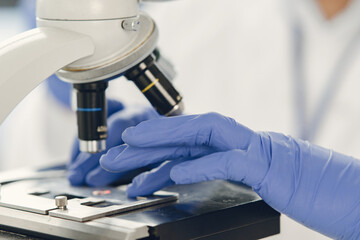 Unrecognizable lab worker inspecting blood sample under microscope