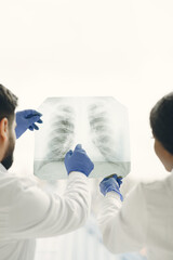 Naklejka premium Doctor and coworker standing and looking at x-rays in clinic