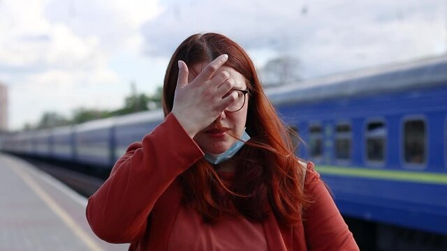 Disgruntled young girl took off her protective medical mask while waiting for public transport at the train station platform