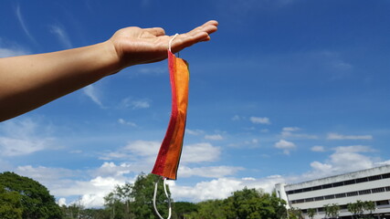 A colorful mask is in a hand with blue background. A concept is for pride month and to encourage LGBTQIA communities around the globe.