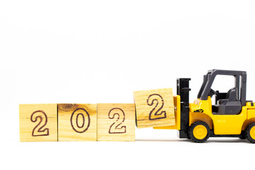 Toy forklift hold letter block 2 to complete word 2022 on wood background