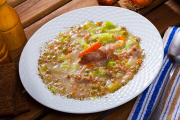 Image of lamb's soup boiled with pearl barley, cabbage and green peas in bowl