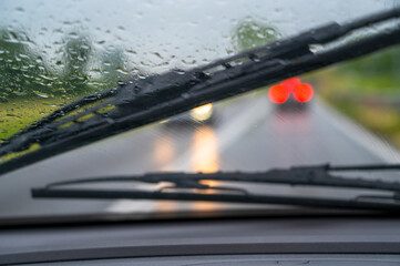 Drops of rain on windscreen of a car driving in the rain. - obrazy, fototapety, plakaty