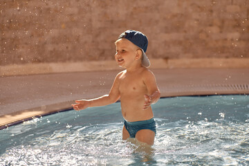 Caucasian cute toddler swims and have fun in small pool for swimming. Concept of summer vacations and fun