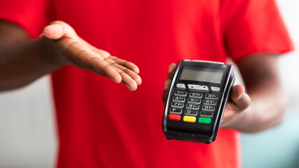 Closeup view of black man holding POS machine for payment