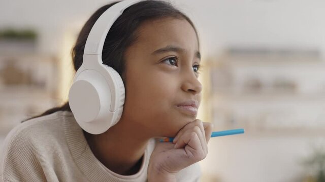 Portrait of thoughtful girl sitting at desk in headphones