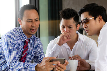 Businessmen or success business team sitting and meeting at table in coffee shop and discuss business plan. On table tablet, smartphone, cup of coffee.