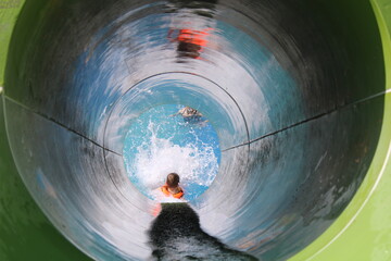 boy slides down a closed pipe in a water park