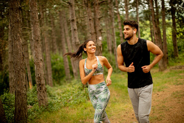 Young fitness couple running at the forest trail