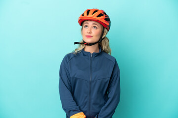 Young cyclist woman isolated on blue background and looking up