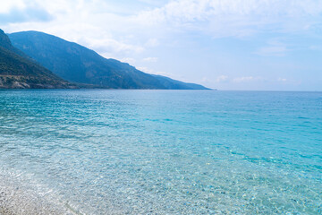 Fototapeta na wymiar Mediterranean sea with mountains on the background. Transparent blue water