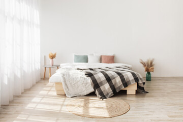 Fototapeta na wymiar Contemporary boho design in minimalist. Bed with pillows and blanket, table with dry plants in vases