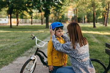 mother and her child in public park preparing to ride a bike