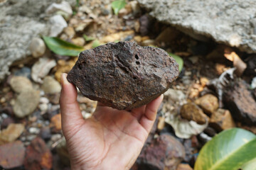 Hand is holding a Psilomelane rock. A hard black manganese oxides including hollandite and...