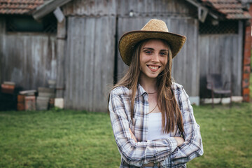 woman rancher standing crossed arms in front of barn