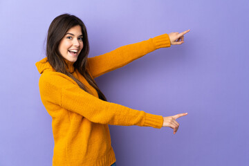 Teenager Brazilian girl over isolated purple background pointing finger to the side and presenting...