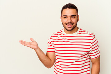 Young caucasian man isolated on white background showing a copy space on a palm and holding another...