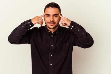 Obraz premium Young caucasian man isolated on white background focused on a task, keeping forefingers pointing head.