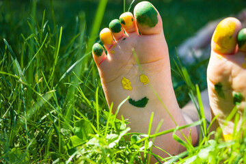 Childs feet on green grass in sunny summer day. Painted kids heels. Happy carefree childhood...