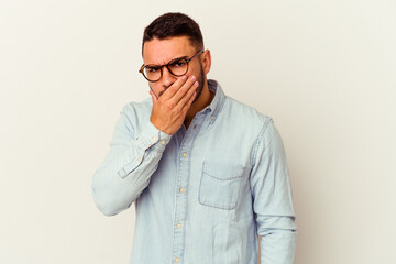 Young caucasian man isolated on white background covering mouth with hands looking worried.