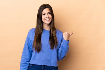 Teenager Brazilian girl over isolated background pointing to the side to present a product